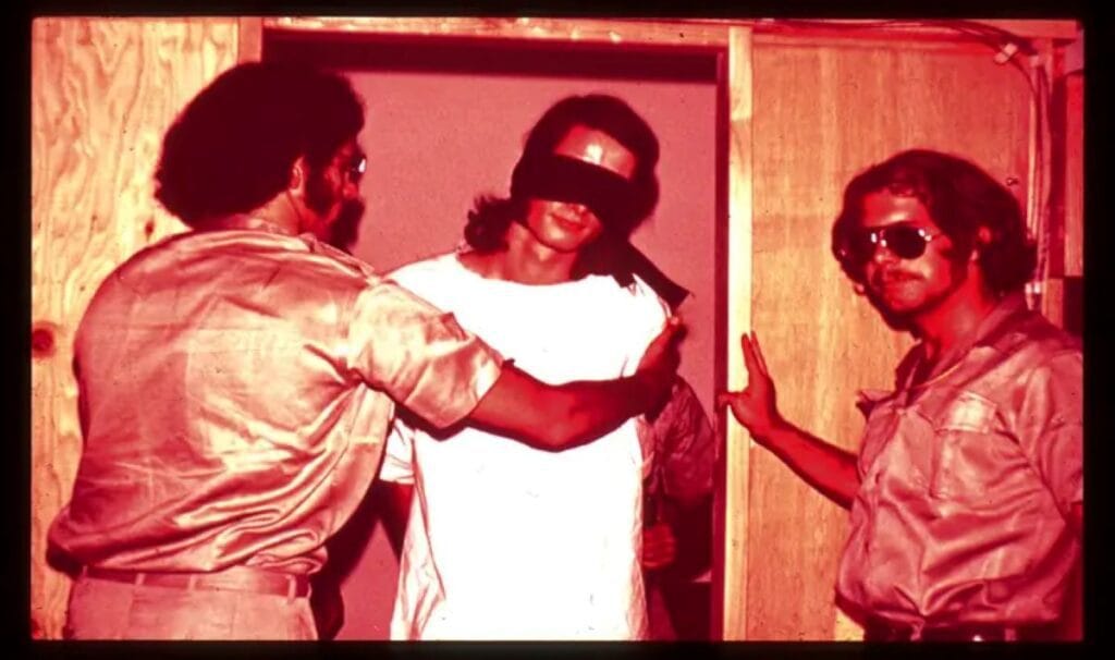 Two guards and one blindfolded prisoner participating in the Stanford University experiment.