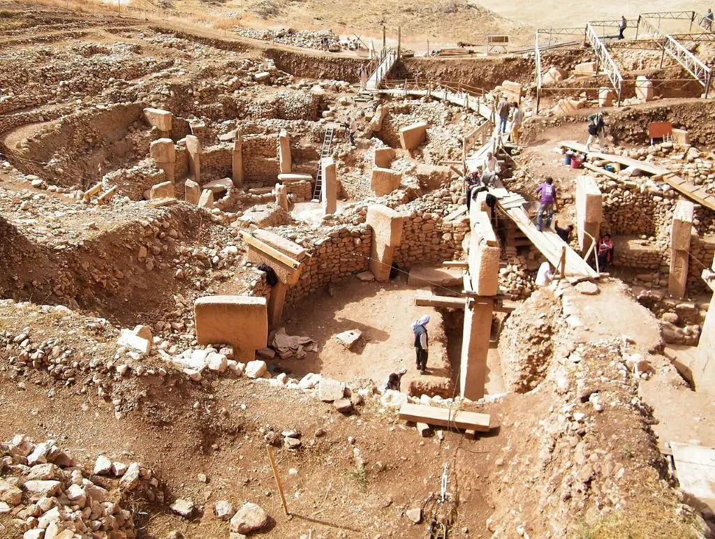A view of the excavation site of Gobekli Tepe, featuring circularly arranged T-shaped stelae and the remains of stone walls.