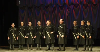A Georgian folk singing group is singing while wearing traditional Georgian attire.